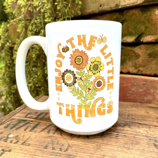 A white, coffeehouse-style Love Letters mug with yellow flowers on it.