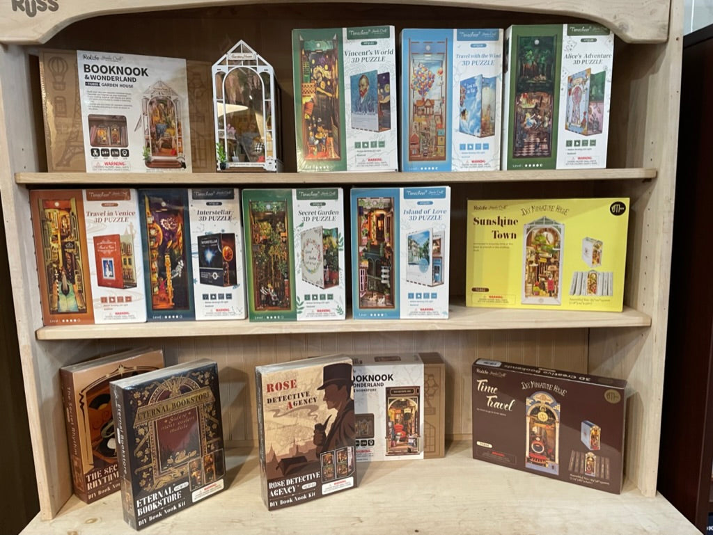 A display of books and puzzles on a wooden shelf.