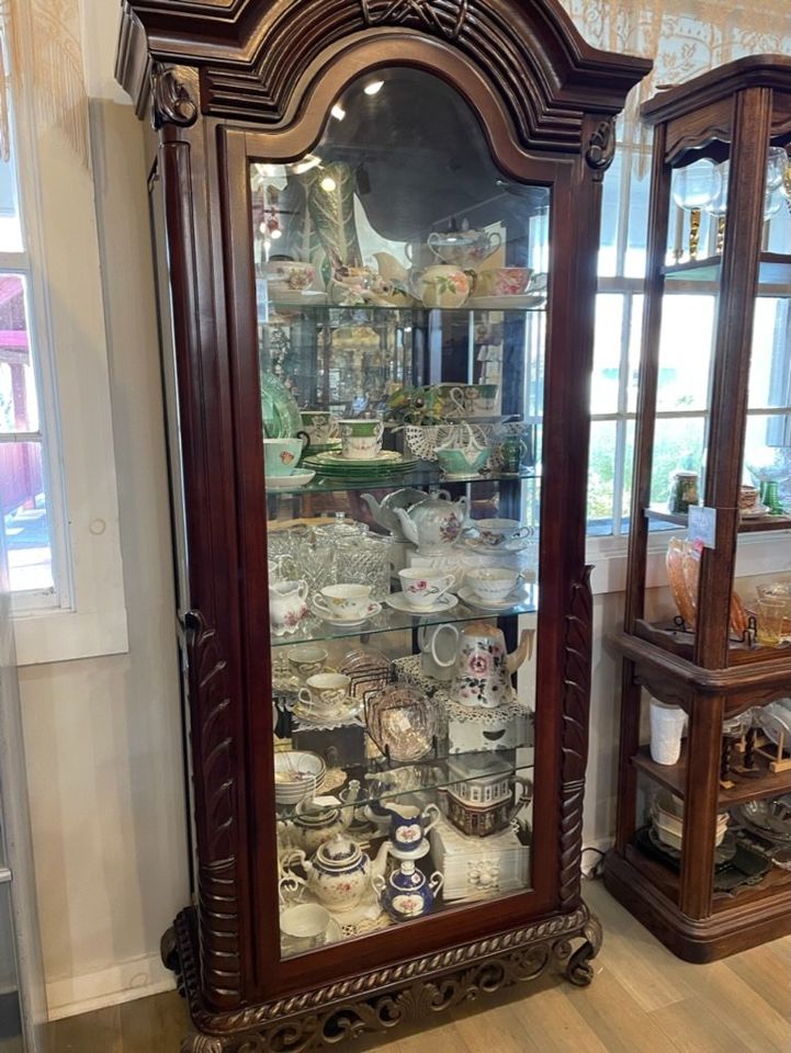 a dark wood curio with a glass door and glass shelves